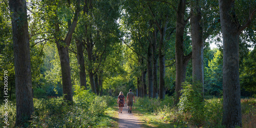 Couple walking on path in a forest in summer in Broekpolder, Vlaardingen, Netherlands