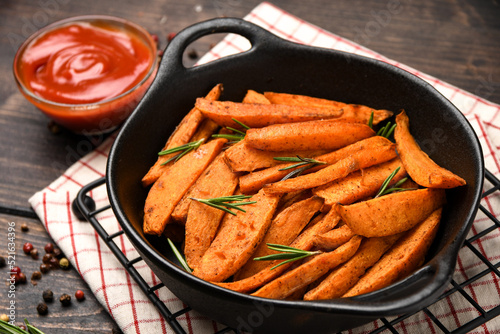 Baked Sweet Potatoes in a Black Pan on a Wooden Background
