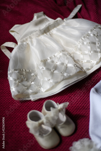 Overhead view of a christening dress and christening shoes on a bed photo