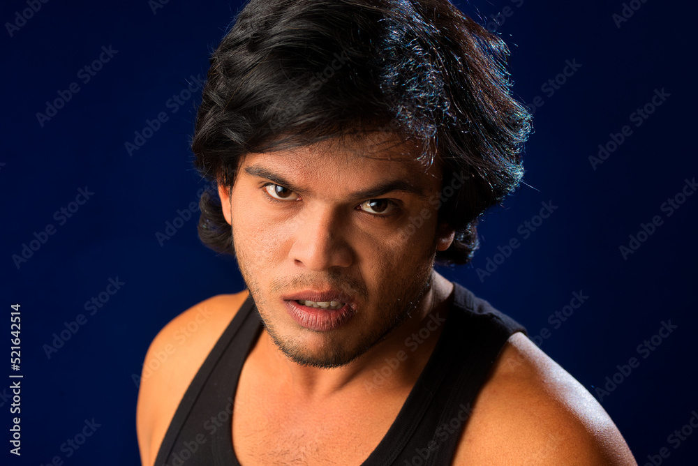Portrait of a young man posing and showing his muscular body. The concept of a healthy lifestyle on blue background. Portrait of a young man posing and showing his muscular body. The concept of a healthy lifestyle on blue background.