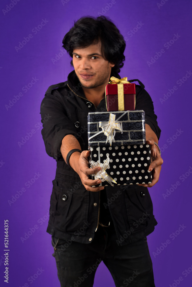 Portrait of young happy smiling handsome man holding gift box on a purple background. Portrait of young happy smiling handsome man holding gift box on a purple background.
