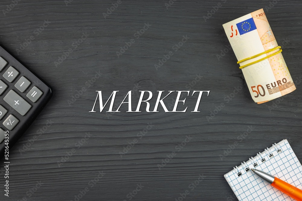 MARKET - word (text) and euro money on a wooden background, calculator, pen and notepad. Business concept (copy space).