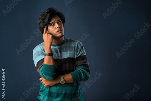 Portrait of a young man thinking on a dark background