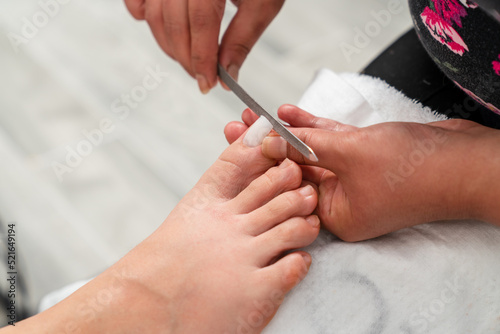Close up photo of toenail filing. Woman get professional pedicure treatment in beauty salon. Beauty and cosmetic concept.