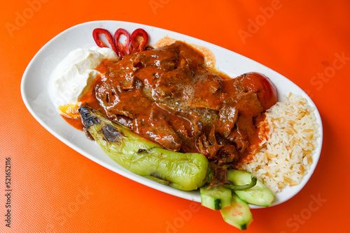 Turkish and Arabic Traditional Ramadan doner kebab with tasty tomato sauce and rice or turkish pilav in white plate on wood table background. ( , Iskender, ekmek arasi pilav ustu doner, doner durum ) photo