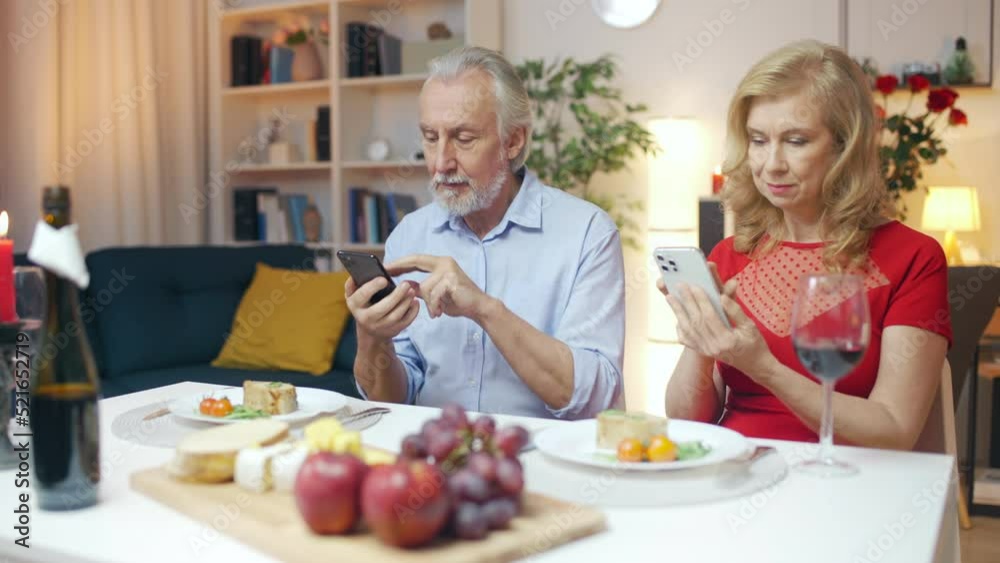 Husband and wife using smartphones instead of talking at romantic dinner Husband and wife using smartphones instead of talking at romantic dinner