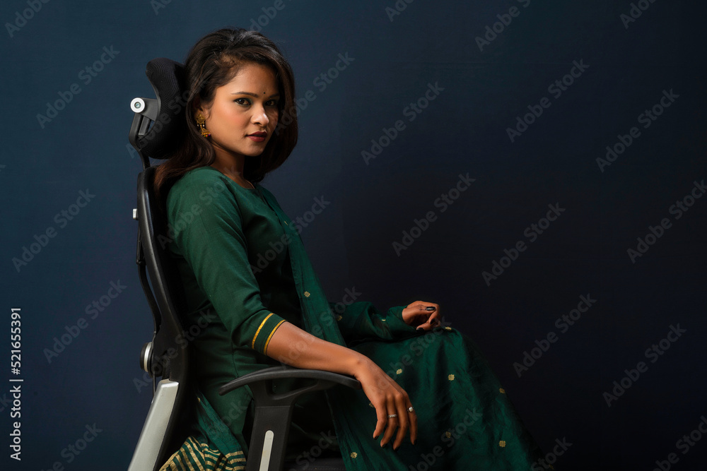A beautiful girl sitting on an executive chair and posing.