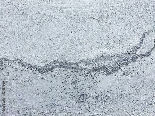 Textured concrete wall with white and blue streaks and gray stripes. Small gray droplets on the surface. Concrete background