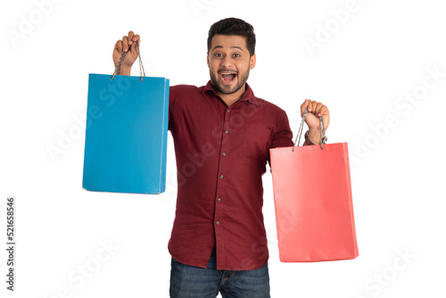 Young handsome man holding and posing with shopping bags on a white background