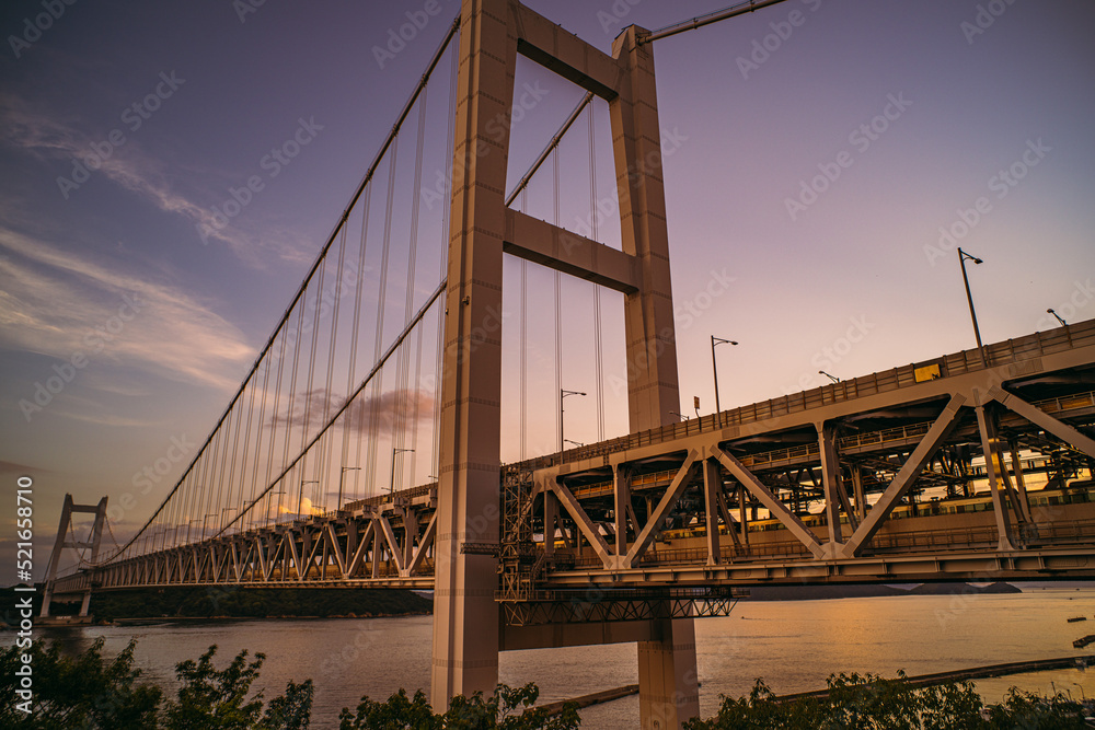 Obraz premium Bridge and train over the Seto Inland Sea at sunset