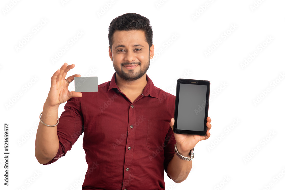 Young smiling man presenting a credit card while using a smartphone or buying online on mobile with a credit card