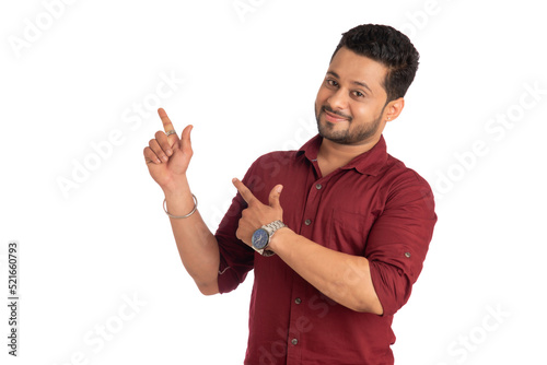 Portrait of a successful cheerful young man pointing and presenting something with hand or finger with a happy smiling face.
