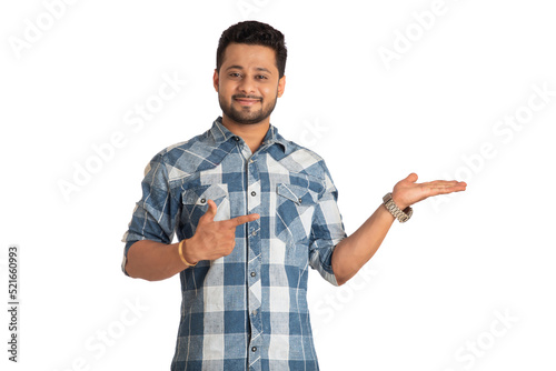 Portrait of a successful cheerful young man holding and presenting something on hand with a happy smiling face.