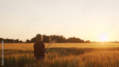 Boy in front of a sunset agricultural landscape. Kid in a countryside field. Childhood, country life, farming and country lifestyle concept.