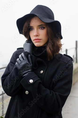 Beautiful woman in black clothes walking outdoors in a mist on autumn day