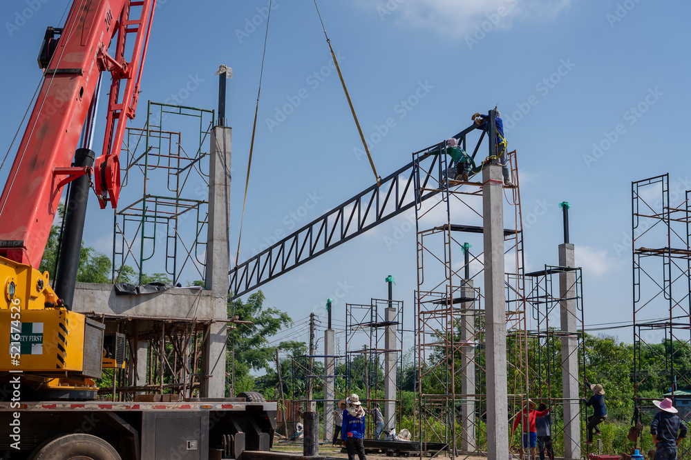Mobile cranes are lifting steel trusses to connect factory roof trusses