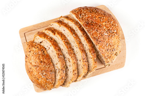 Round whole-grain bread made of wheat flour with the addition of seeds, cut into pieces, lies on a wooden board on a white insulated background. Sourdough bread, without yeast. View from above.