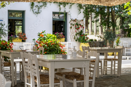 Greek outdoors tavern with table and chair at Kithira island Milopotamos village. Pots with flowers. © Rawf8