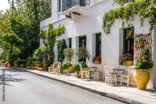 Fototapeta Naklejka Na Ścianę i Meble -  Greek outdoors cafe, table and chair on pavement at Kythera island Milopotamos. Pots with flowers.