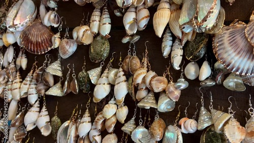 earrings and various jewelry made from real ocean shells They hang on the counter sparkling in different colors also gold trim at Ocean Vancouver Canada Goats on the roof country market in Coombs. photo