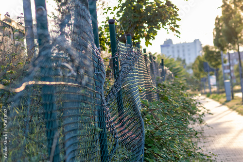 Green damaged wire-mesh fence is ruined after collision with car accident as crushed fence for car insurance and property insurance and loses security and safety with vandalism and barrier demolition photo