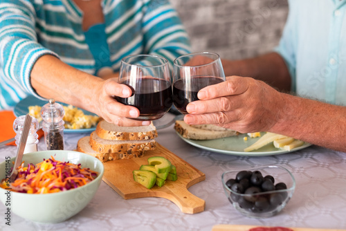 Closeup on caucasian senior couple sitting at the table having brunch at home toasting with glasses of wine