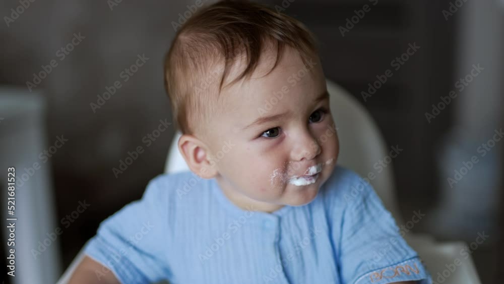 Funny little toddler being fed from spoon. Adorable baby with porridge on his face waits patiently for another spoon. Funny little toddler being fed from spoon. Adorable baby with porridge on his face waits patiently for another spoon.