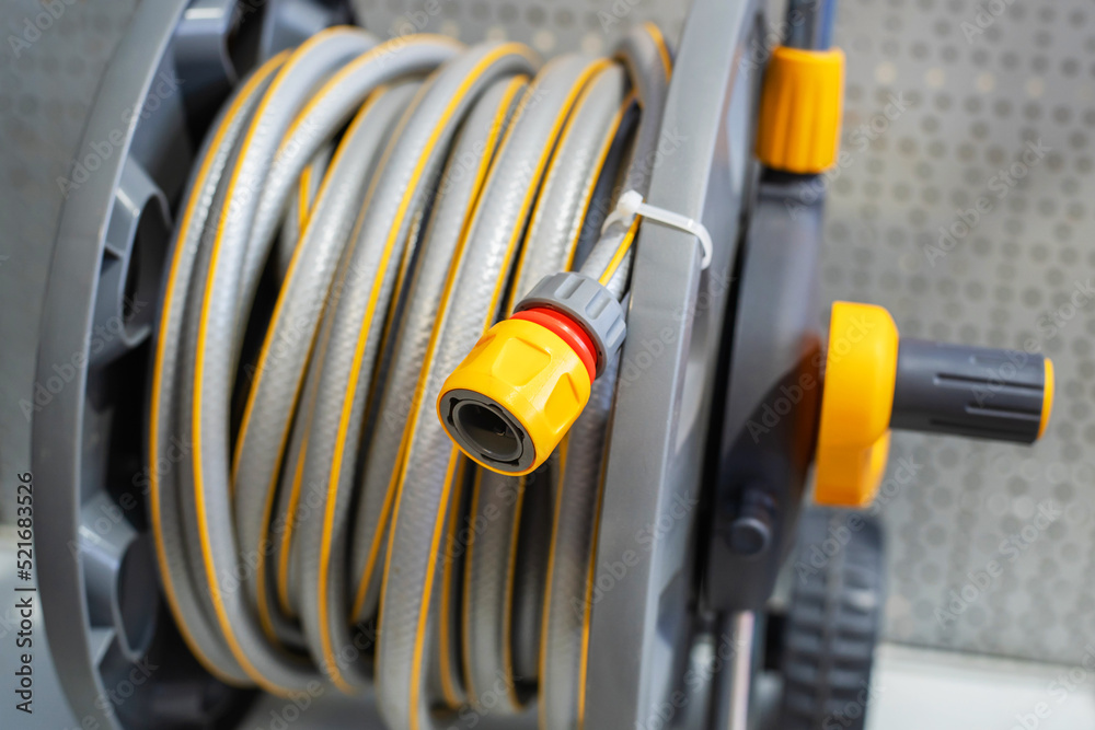 Garden hose on a plastic reel. Convenient equipment for watering plants. Close-up. selective focus Garden hose on a plastic reel. Convenient equipment for watering plants. Close-up. selective focus
