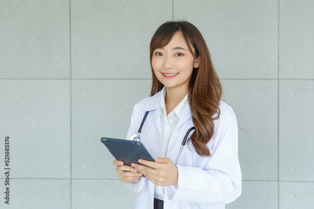 Portrait of beautiful and cheerful good mood young lady asian doctor dressed uniform smiling arm stethoscope while using tablet on loft wall background. Portrait of beautiful and cheerful good mood young lady asian doctor dressed uniform smiling arm stethoscope while using tablet on loft wall background.