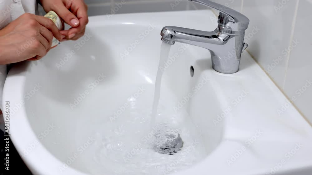 Euro banknotes on the background of running water in the tap in the bathroom. Cost calculation according to the tariff concept. Household efficiency and cost idea. The concept of saving water Euro banknotes on the background of running water in the tap in the bathroom. Cost calculation according to the tariff concept. Household efficiency and cost idea. The concept of saving water