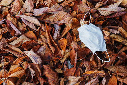 Droht im Herbst eine neue Corona Welle. Eine Schutzmaske auf Herbstlaub