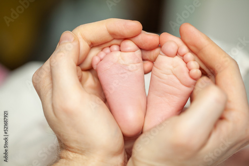 Daddy's hands touches the legs of his adorable newborn daughter