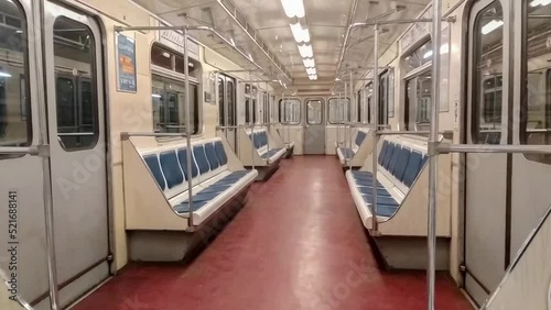 Inside view of the moving subway train carriage, empty seats in a subway car. No passengers aboard.