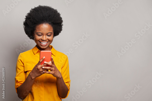 Smiling woman texting on her phone. Happy black model using smartphone, messaging or browsing social networks