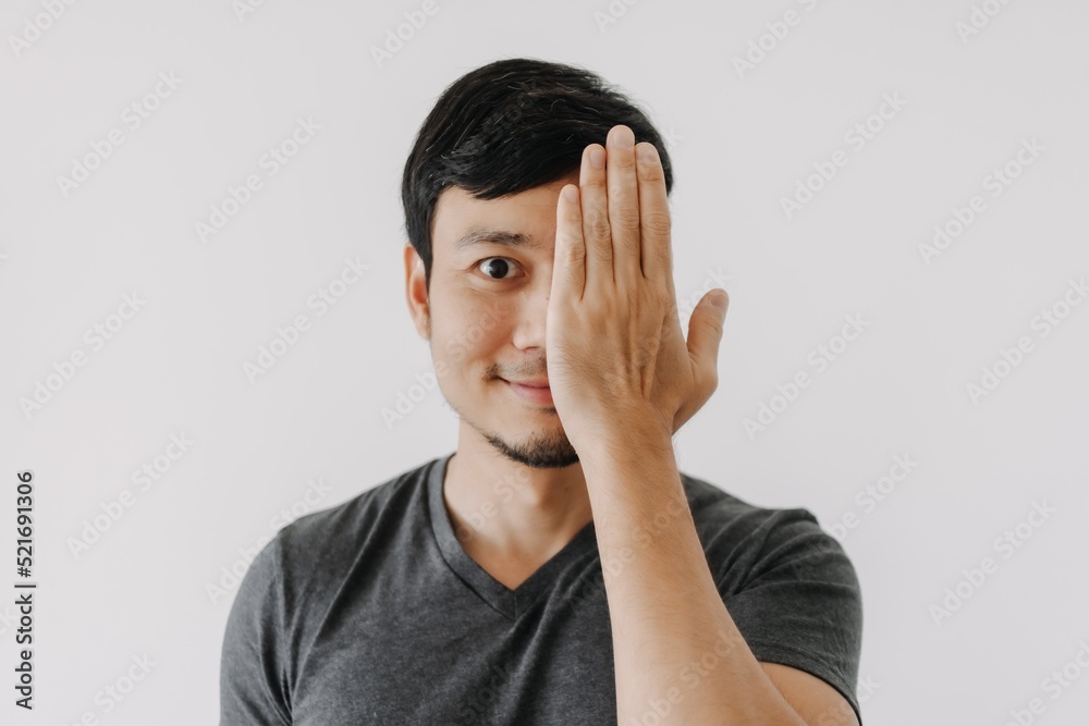 Smile face happy asian man with one eye close cover by hand isolated on white Smile face happy asian man with one eye close cover by hand isolated on white