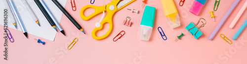 Online study, distantly learning class. Long horizontal banner. Online education, back to school, freelancer work concept. School supplies, stationery accessories on pink background. Flatlay, top view