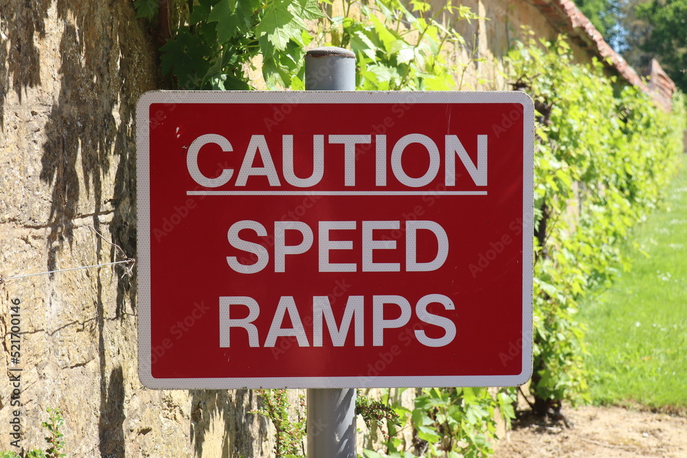 Foto de A red road sign warning of speed ramps ahead by the exit of a