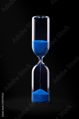 Hourglass with blue sand on black background