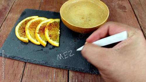 hand writing the word MEZCAL on a stone plate with a jicara bowl of mezcal photo