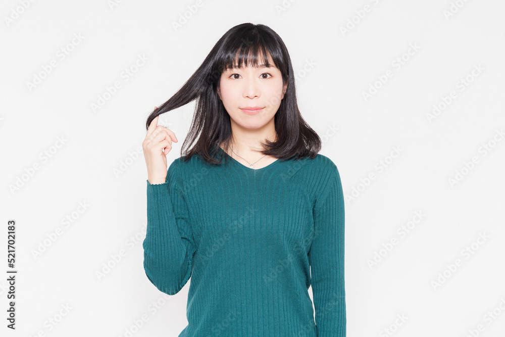 白背景の前に立って髪の毛を触っている女性 白背景の前に立って髪の毛を触っている女性