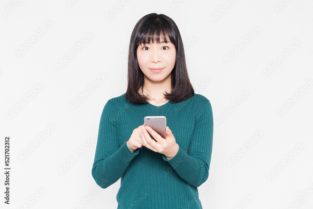 白背景の前でスマホを操作している女性