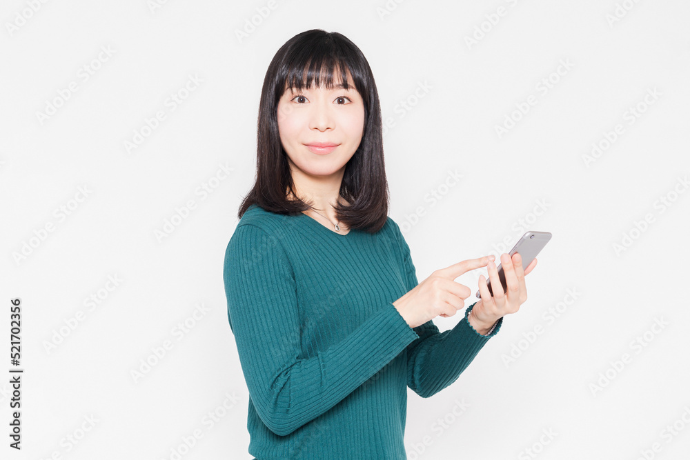 白背景の前でスマホを操作している女性