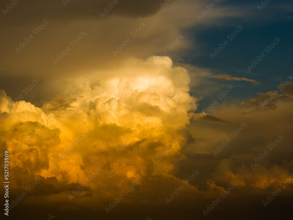 the outer cloud of the storm front at the hour of the beginning of sunset is illuminated by the rays of the low sun on a summer day
