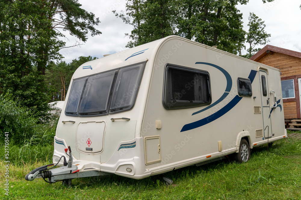 Camper trailer for traveling standing on shore of the lake in summer