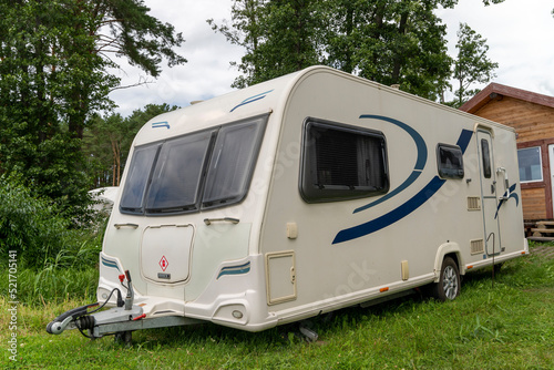 Camper trailer for traveling standing on shore of the lake in summer