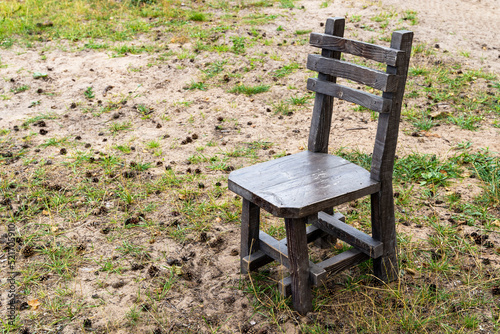 a sturdy powerful rough wooden chair standing on the grass in the yard