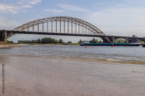 Cargo ship sails under the Waal bridge (Waalbrug) near Nijmegen at very low tide. 