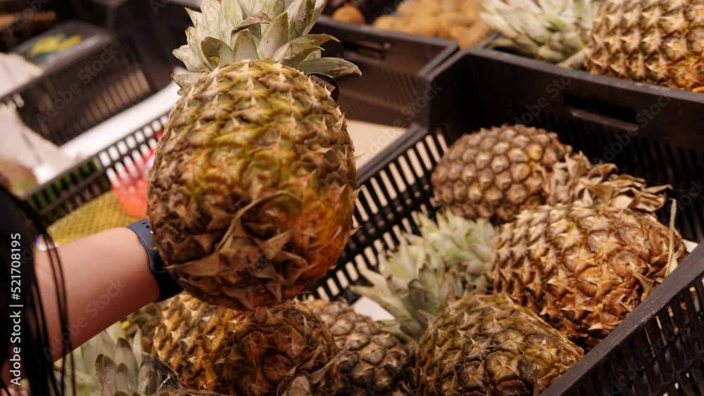 Close-up of a woman holding a pineapple in a supermarket.