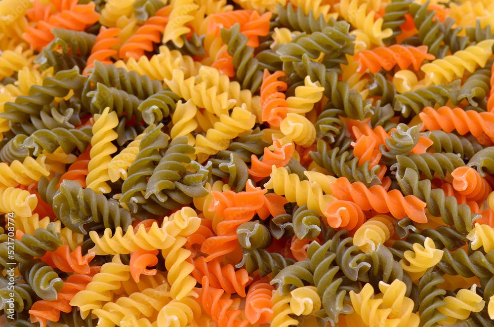 white-red-green fusilli pasta with spinach and tomato extract food background closeup