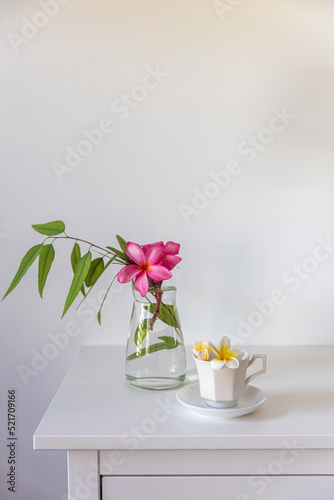Wallpaper Mural Plumberia rumba in a coffe cup, eucalyptus branch in a vase and cup of coffee on a white table against a wall with two frames. Ready layout. Vertical frame. Space for text Torontodigital.ca